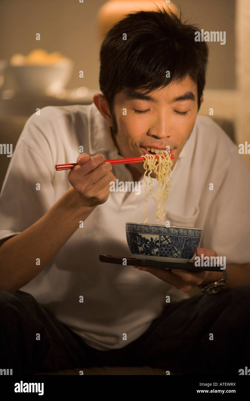 Young man eating noodles Stock Photo Alamy