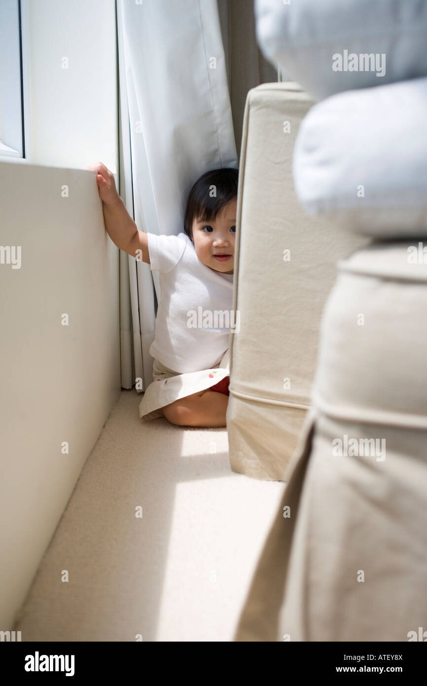 Young girl hiding behind sofa Stock Photo Alamy
