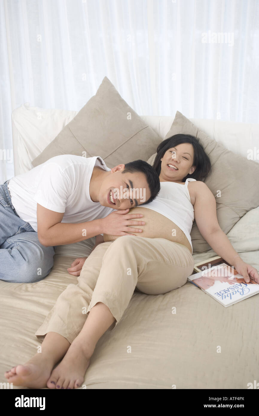 High angle view of a mid adult man lying on the bed with his pregnant ...