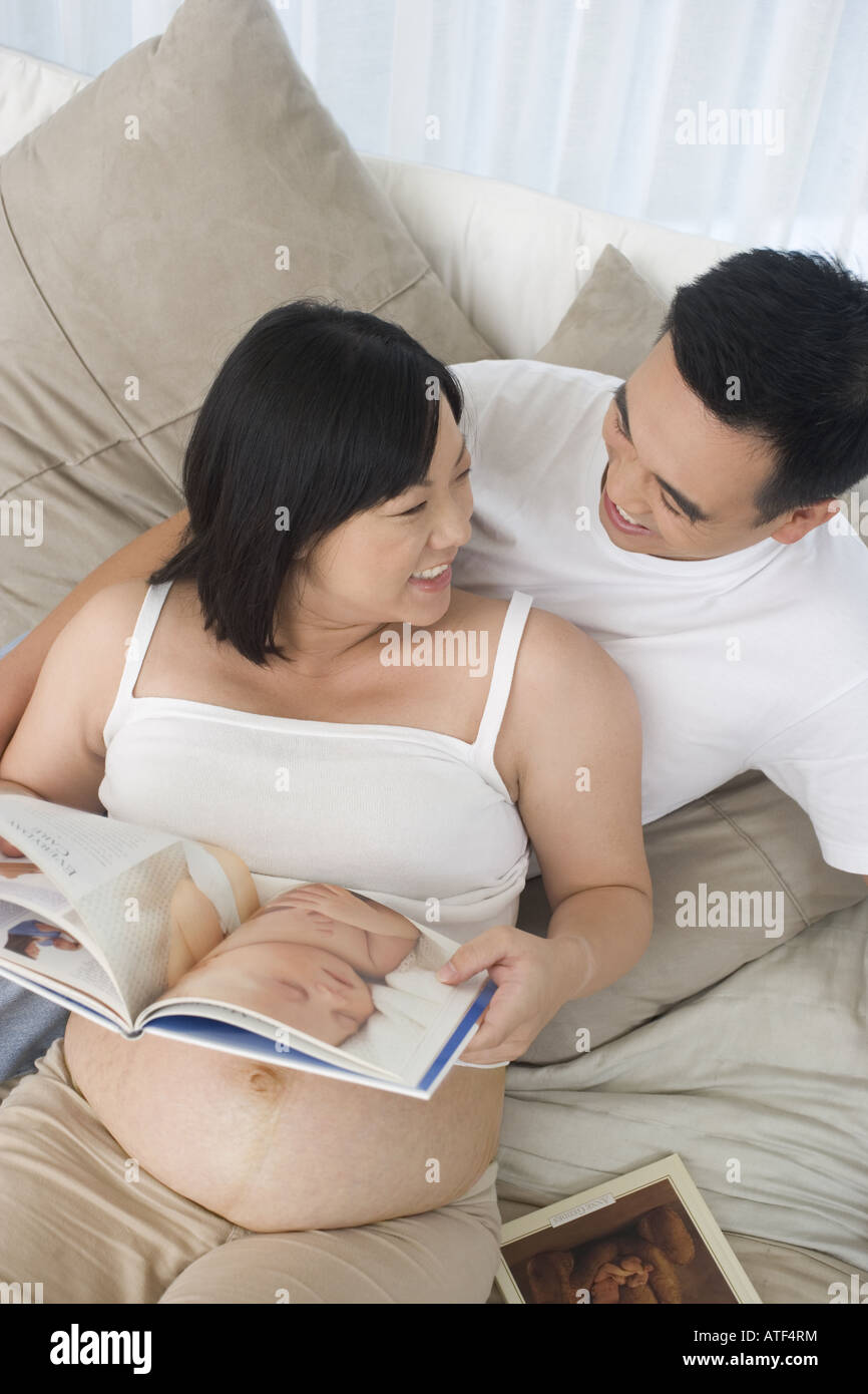High angle view of a mid adult man lying on the bed with his pregnant ...