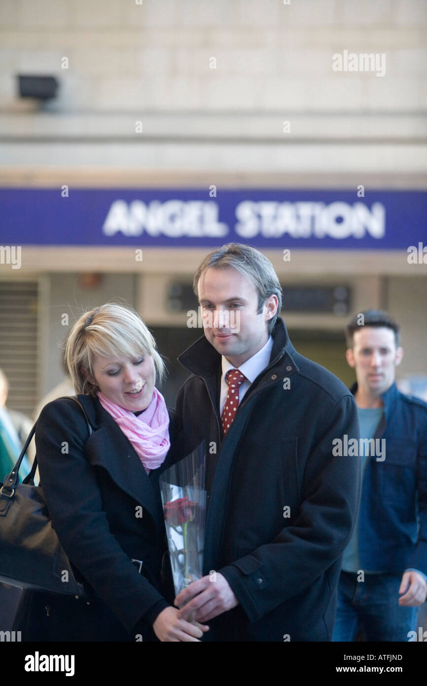 A young professional couple meet outside Angel Underground Station Islington London Stock Photo