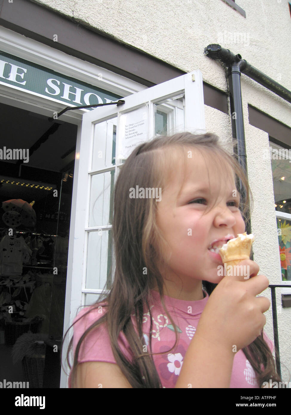 Child eating ice cream outside shop with prohibitive sign Stock Photo