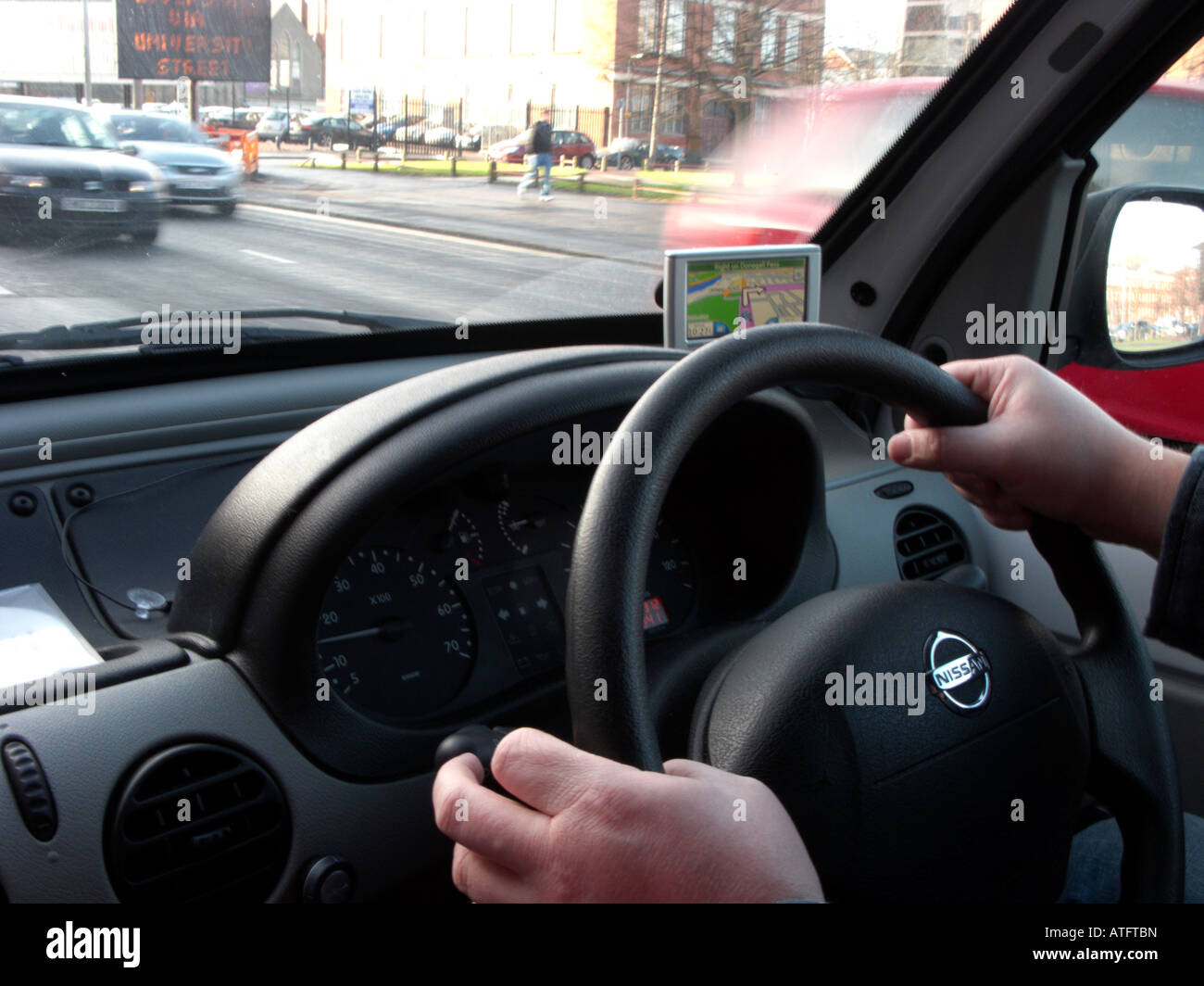mans hand on the top of a steering wheel of a van driving through Belfast City Centre indicating turn following sat nav Stock Photo
