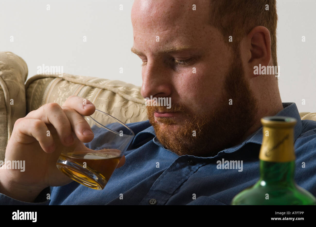 depressed tired alcoholic young man drinking Irish whiskey alcohol