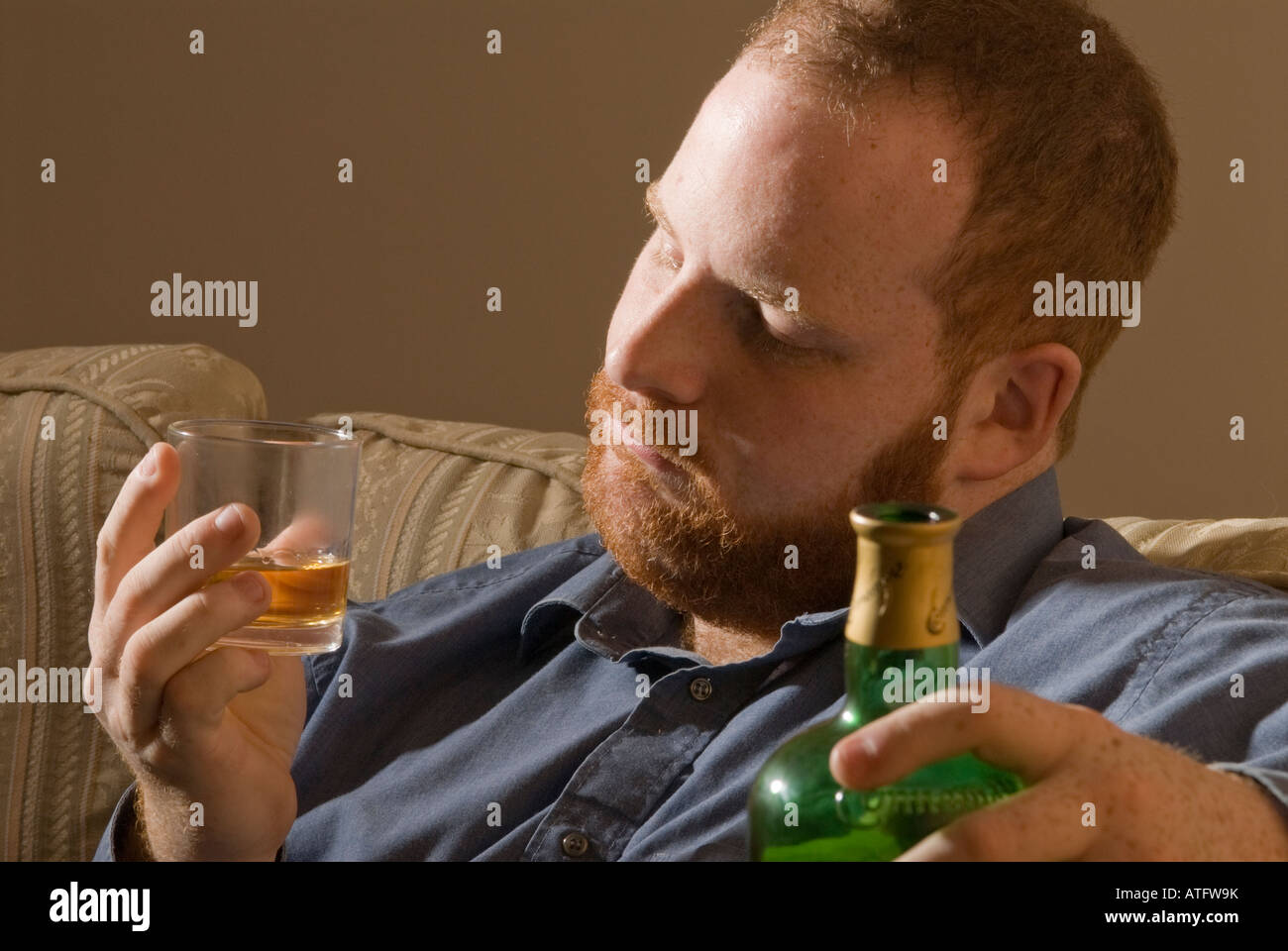 depressed tired alcoholic young man drinking Irish whiskey alcohol