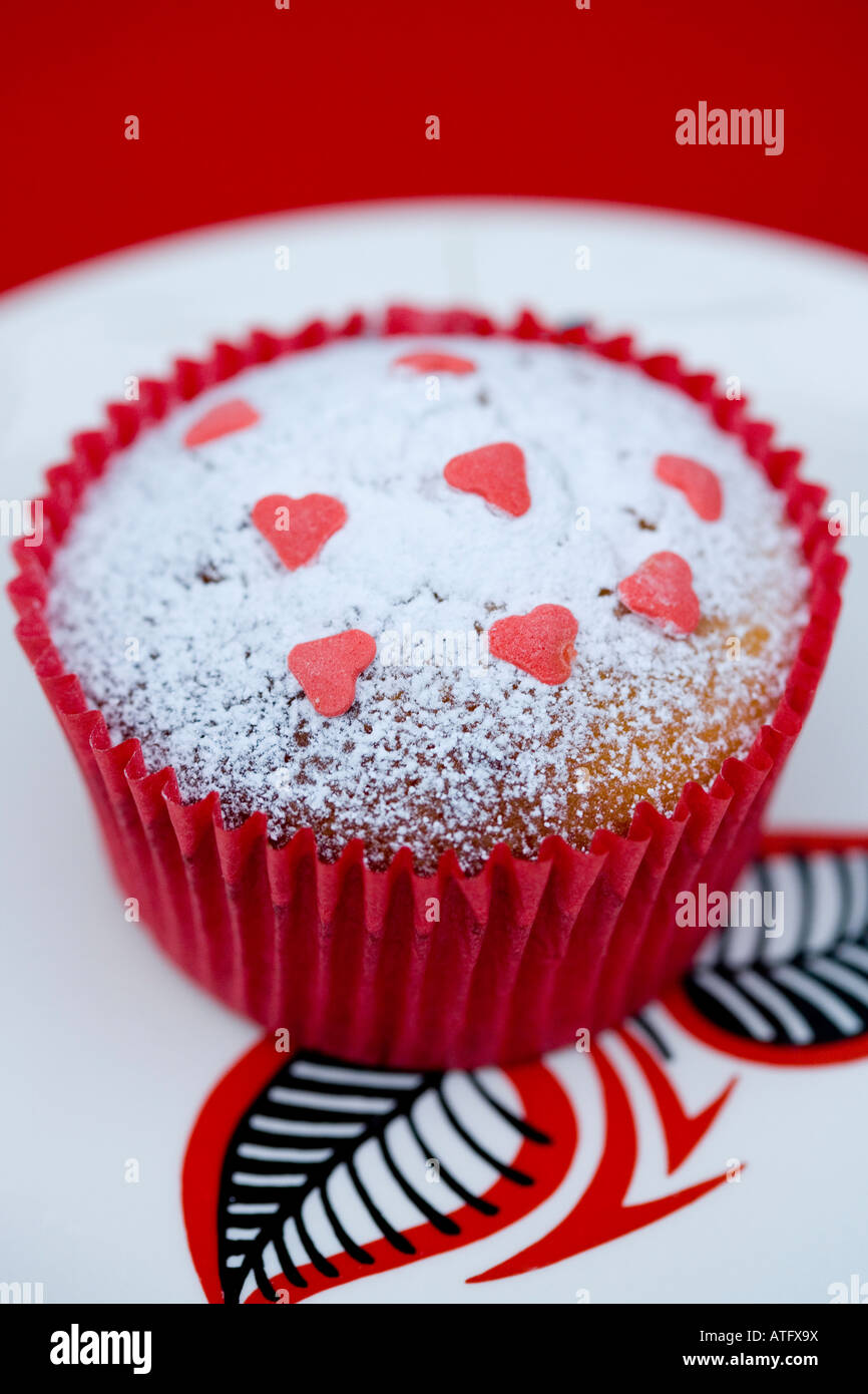 Home baked fairy cake with sugar hearts and dusted icing sugar presented on a vintage china plate (Wade china] Stock Photo