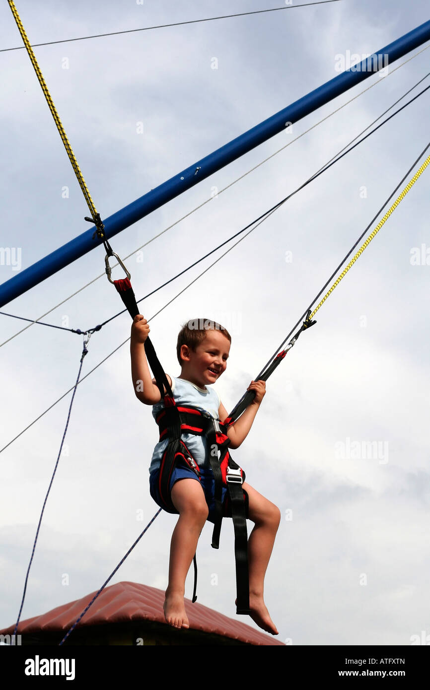 Young boy on bungee bounce swings at safety harness and ropes Stock