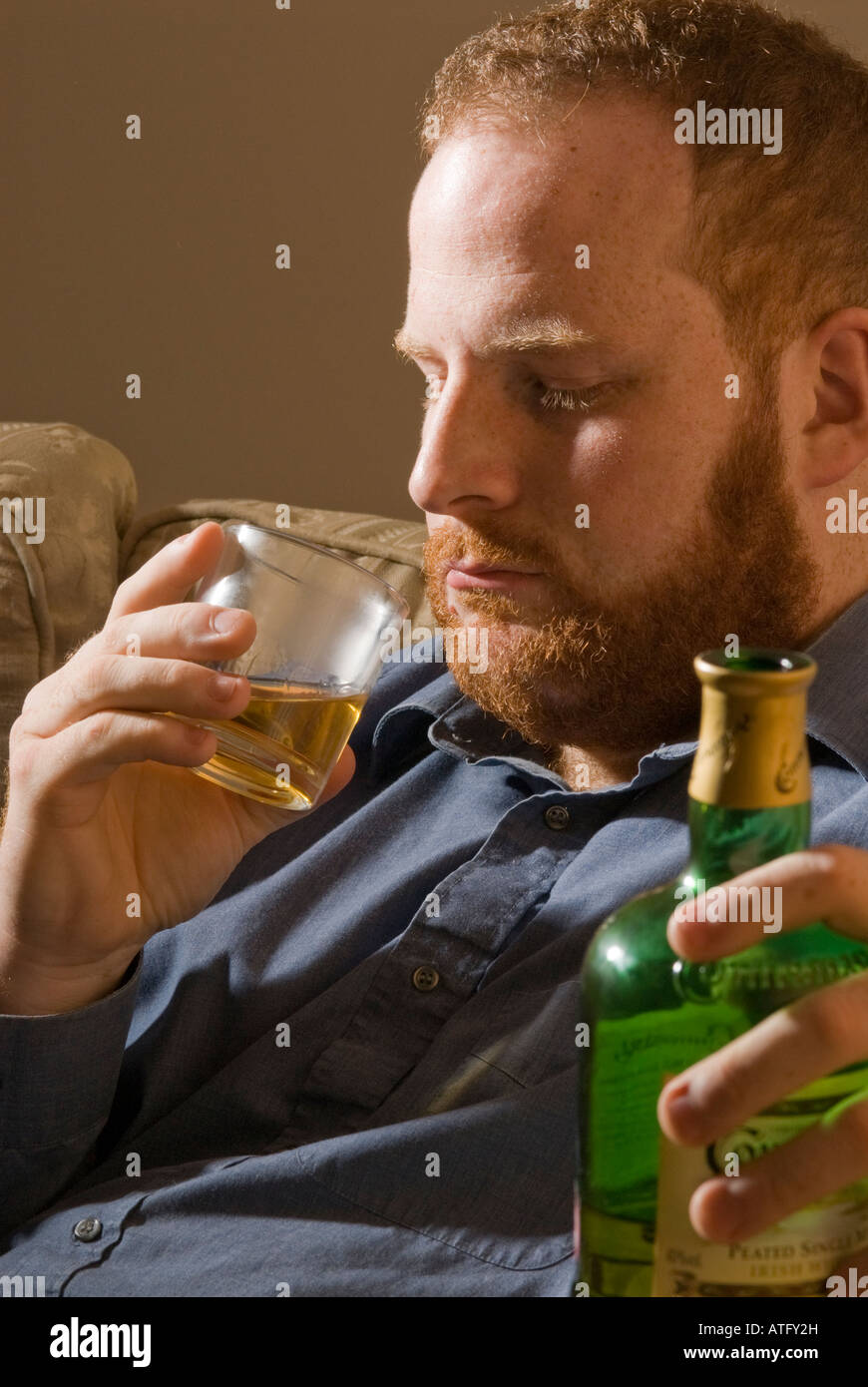 depressed tired alcoholic young man drinking Irish whiskey alcohol