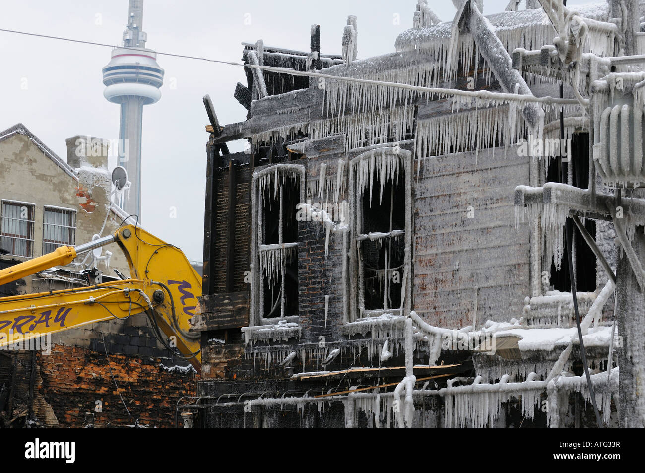 Demolition with excavator after Queen street west fire in Toronto on February 20 2008 charred house with icicles and CN tower Stock Photo
