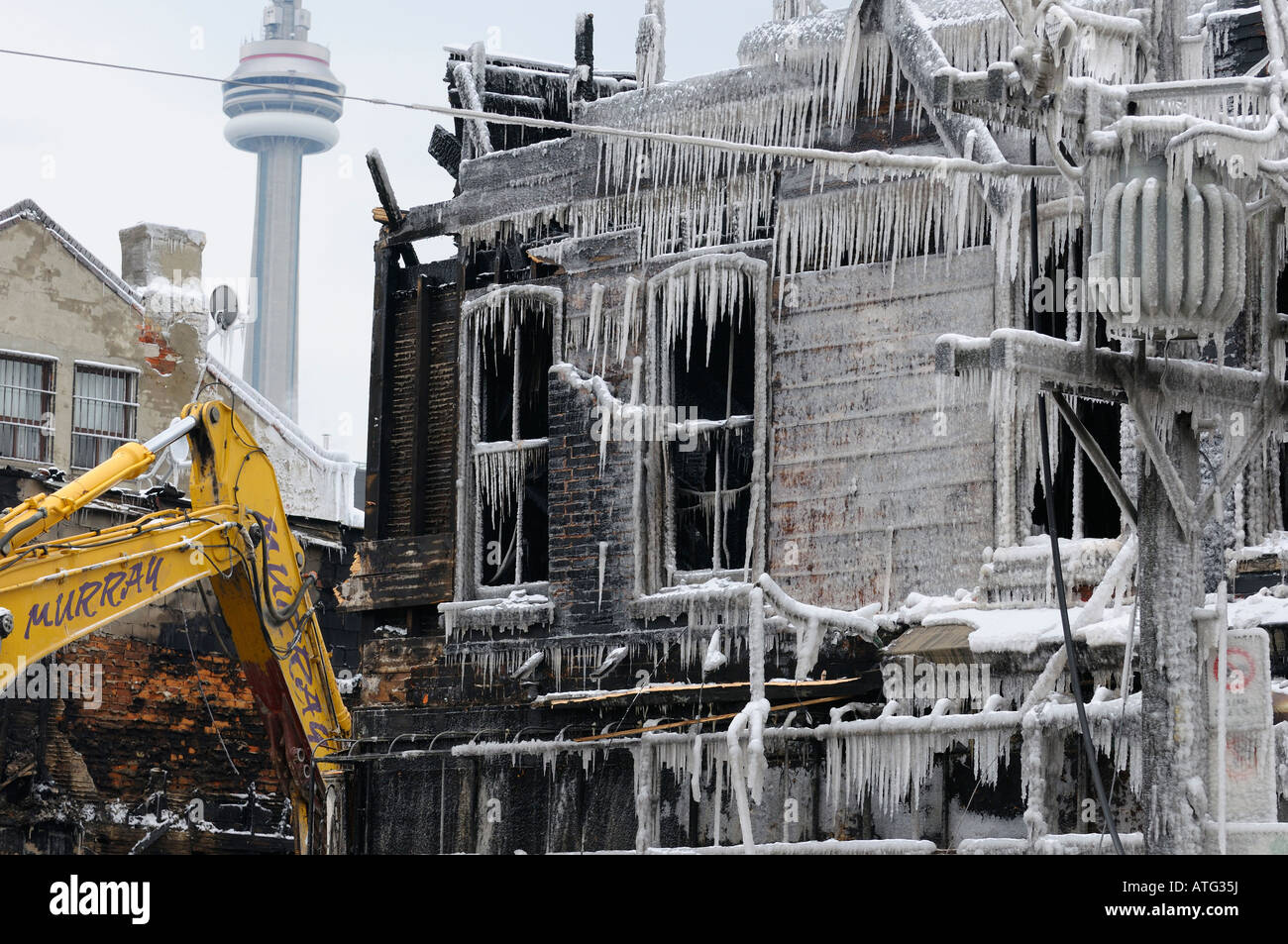 Caterpillar demolishing Victorian buildings after Queen street west fire in Toronto February 20 2008 with icicles and CN tower Stock Photo
