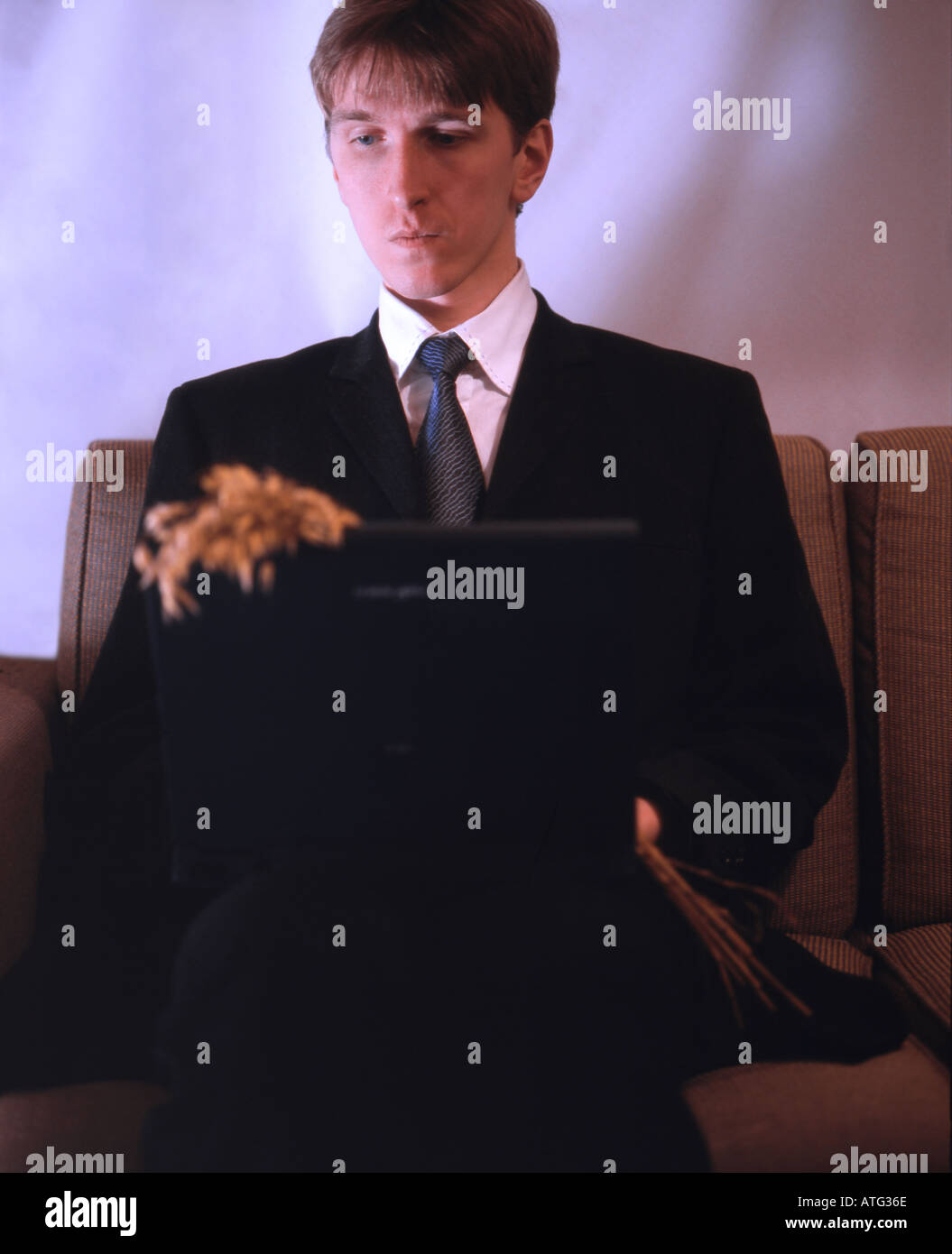 Man in suit with laptop and bouquet Stock Photo