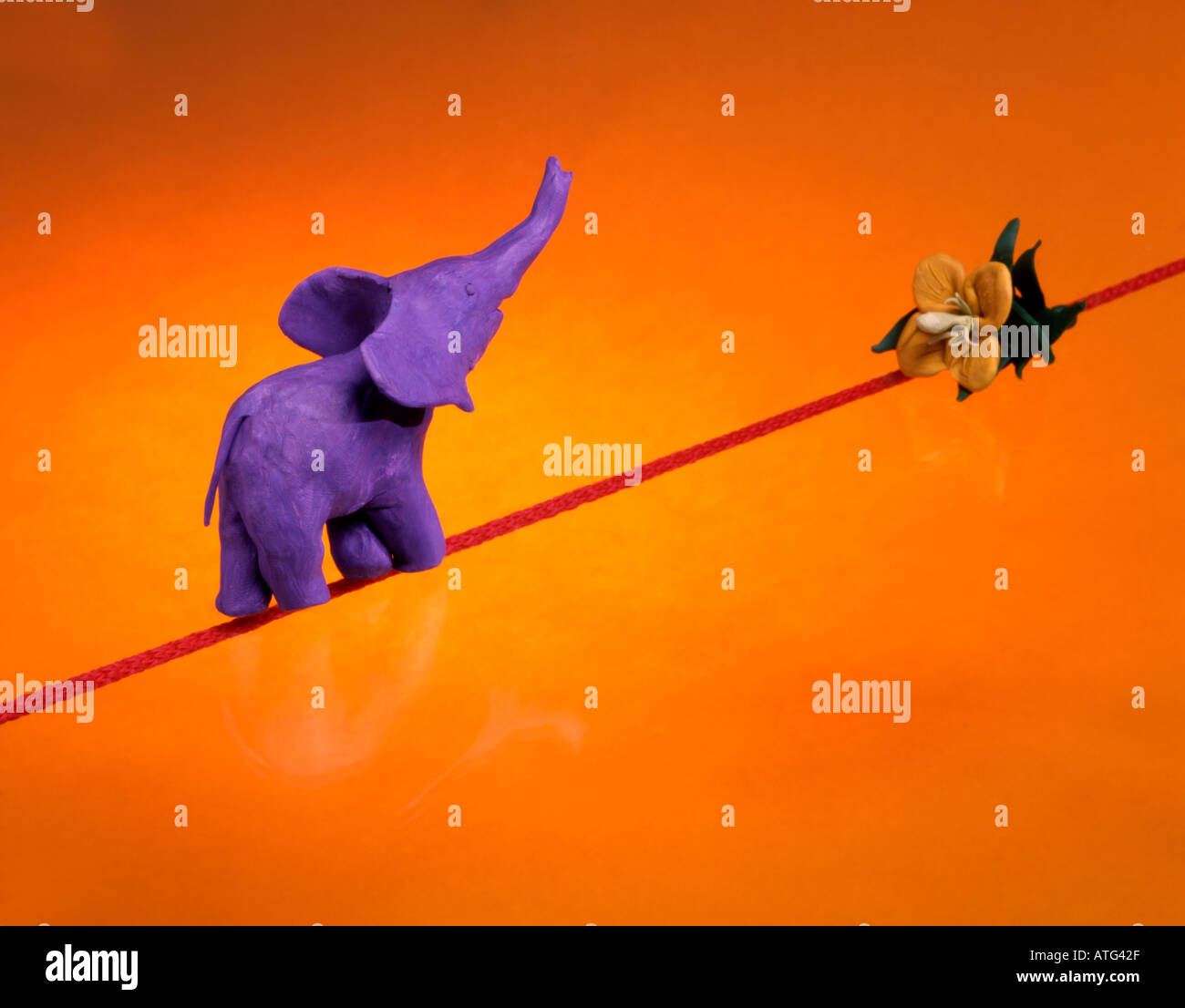 Toy elephant walking on a rope towards a flower. Concept of movement ...