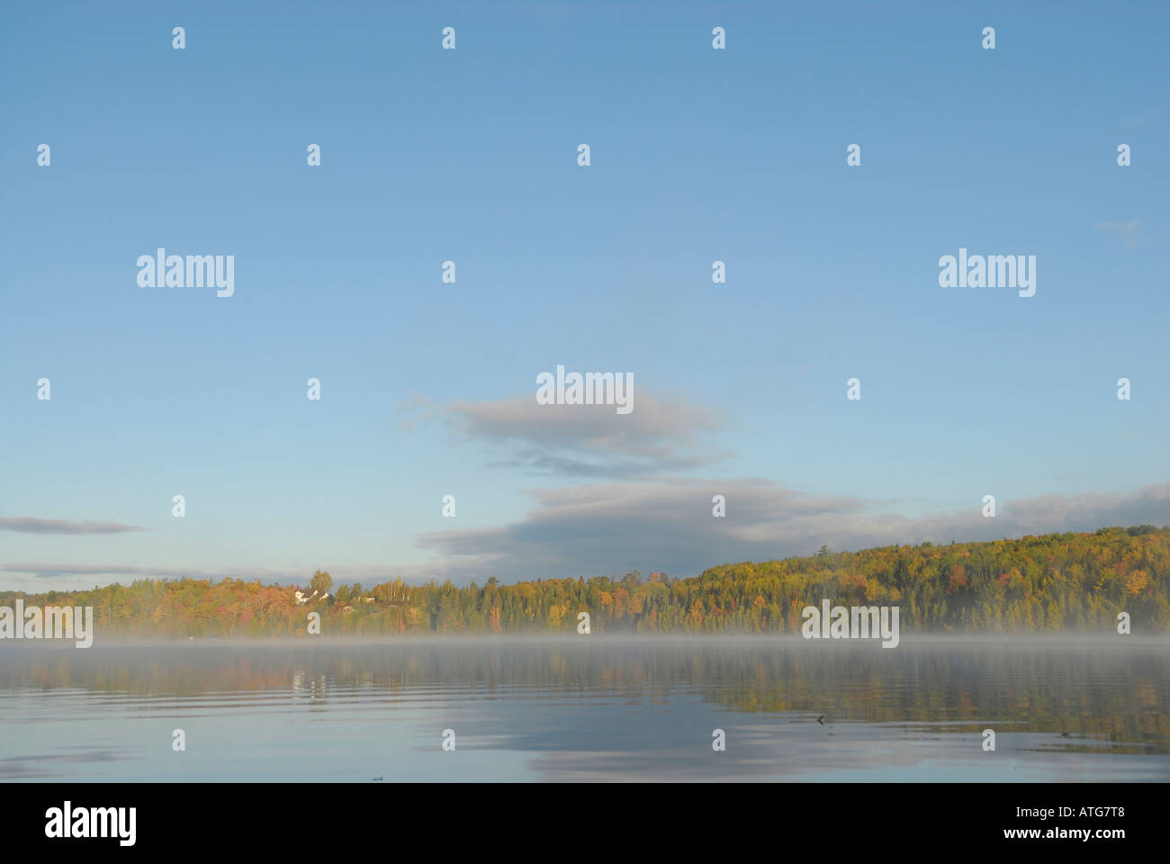 Stock image of a lake with water like glass on an early fall morning with mist in New Brunswick Canada Stock Photo