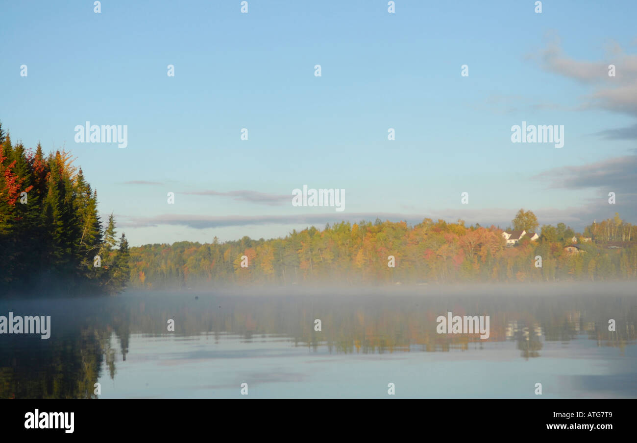 Stock image of a lake with water like glass on an early fall morning with mist in New Brunswick Canada Stock Photo