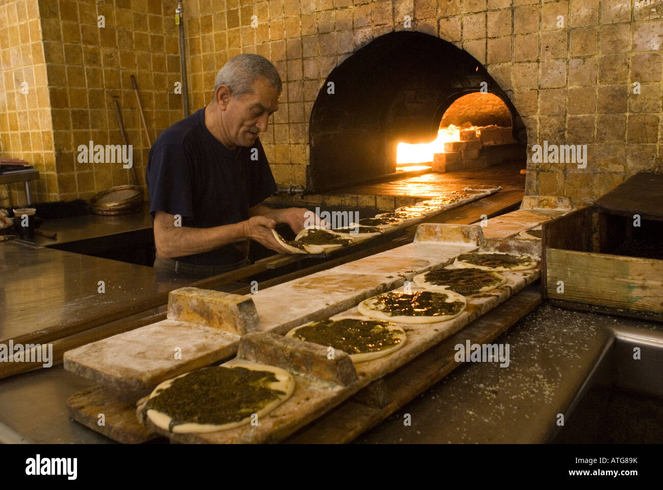 An Israeli Arab man placing traditional Manakish za'atar
