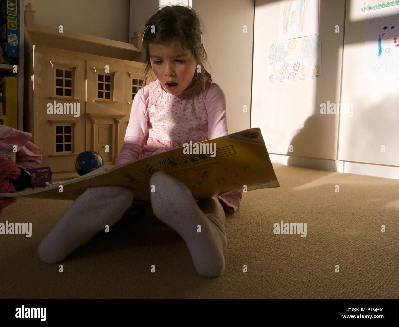 Child sitting on the floor reading music Stock Photo
