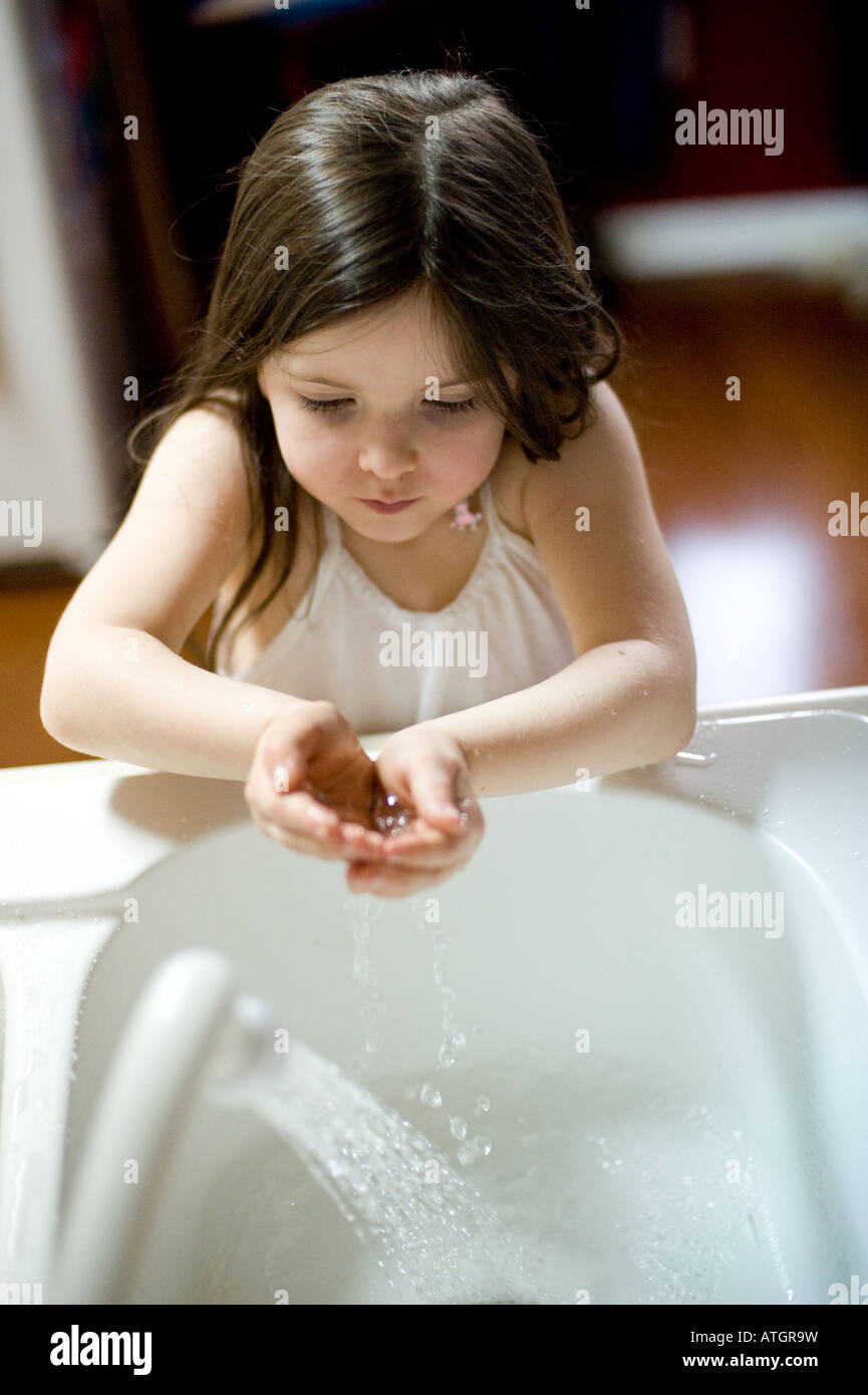 A young girl washes her hands under running water in a sink Stock Photo ...