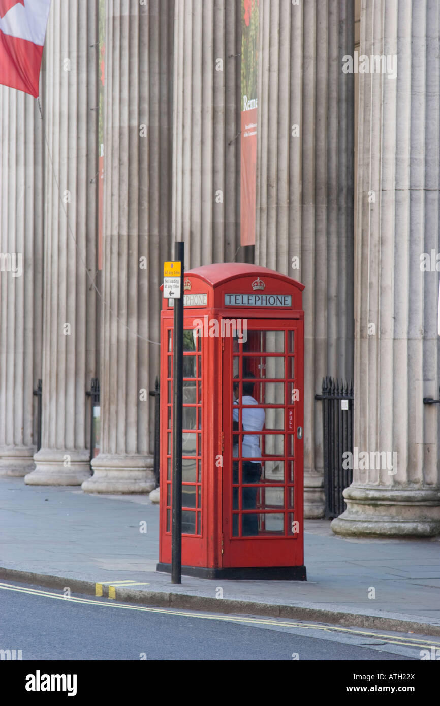 Traditional red London telephone box with fluted stone columns in the background Stock Photo