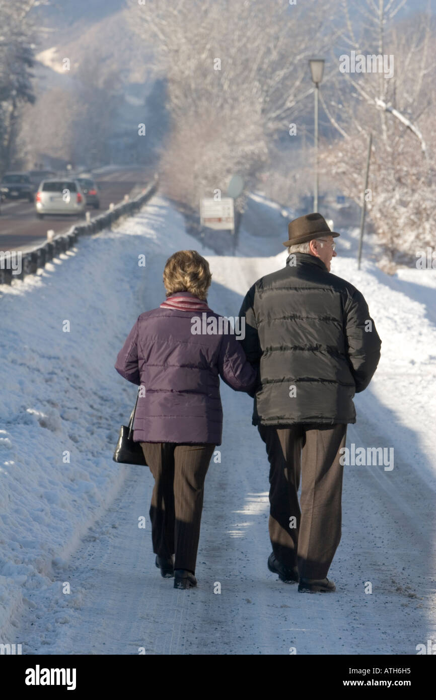 Elderly couple walking on snow covered road Stock Photo