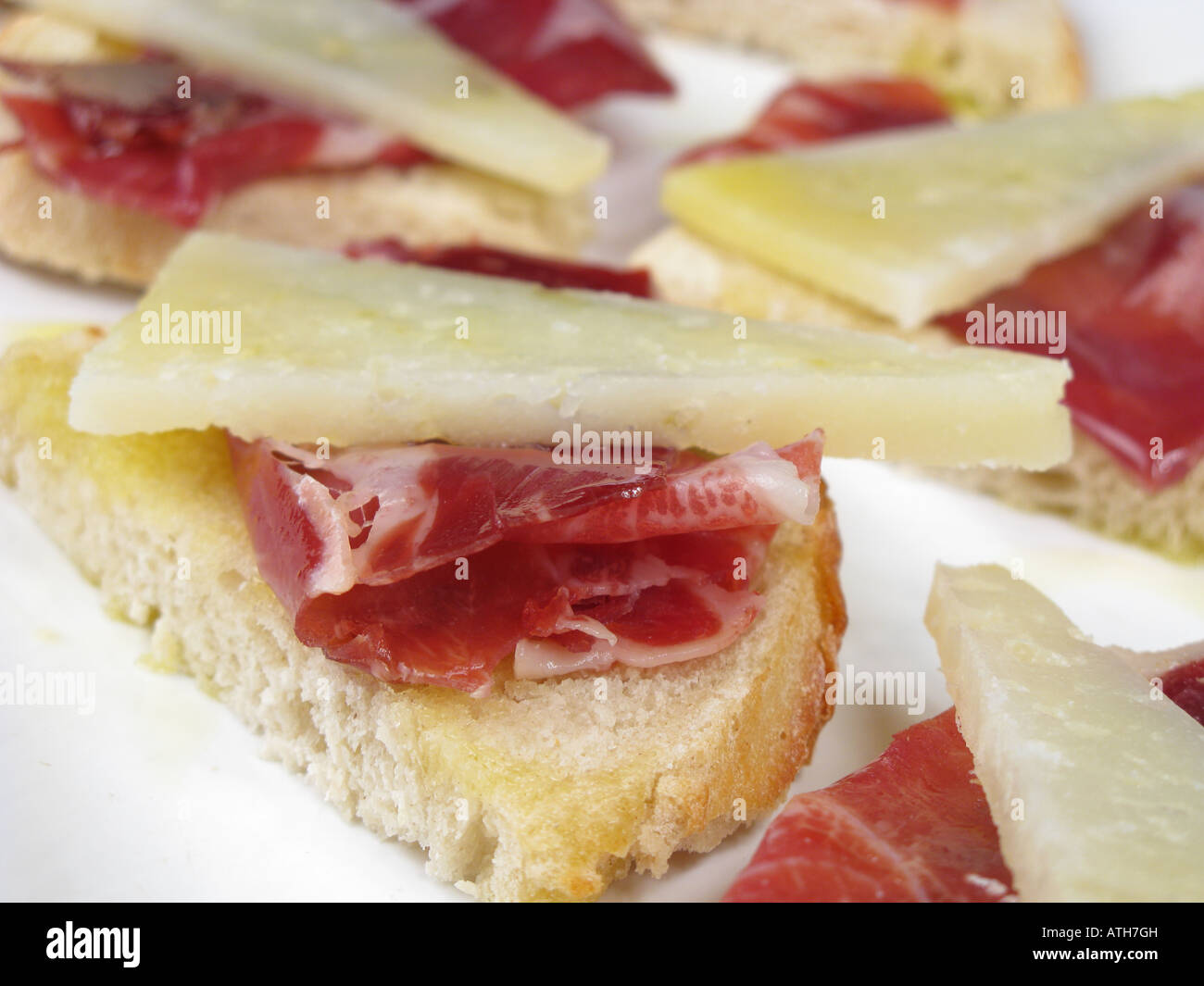 Spanish style tapa of sliced Jamon Iberico de Bellota and Manchego cheese on crusty stonebaked bread. Stock Photo