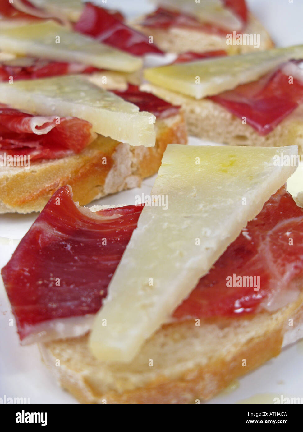 Spanish style tapa of sliced Jamon Iberico de Bellota and Manchego cheese on crusty stonebaked bread. Stock Photo