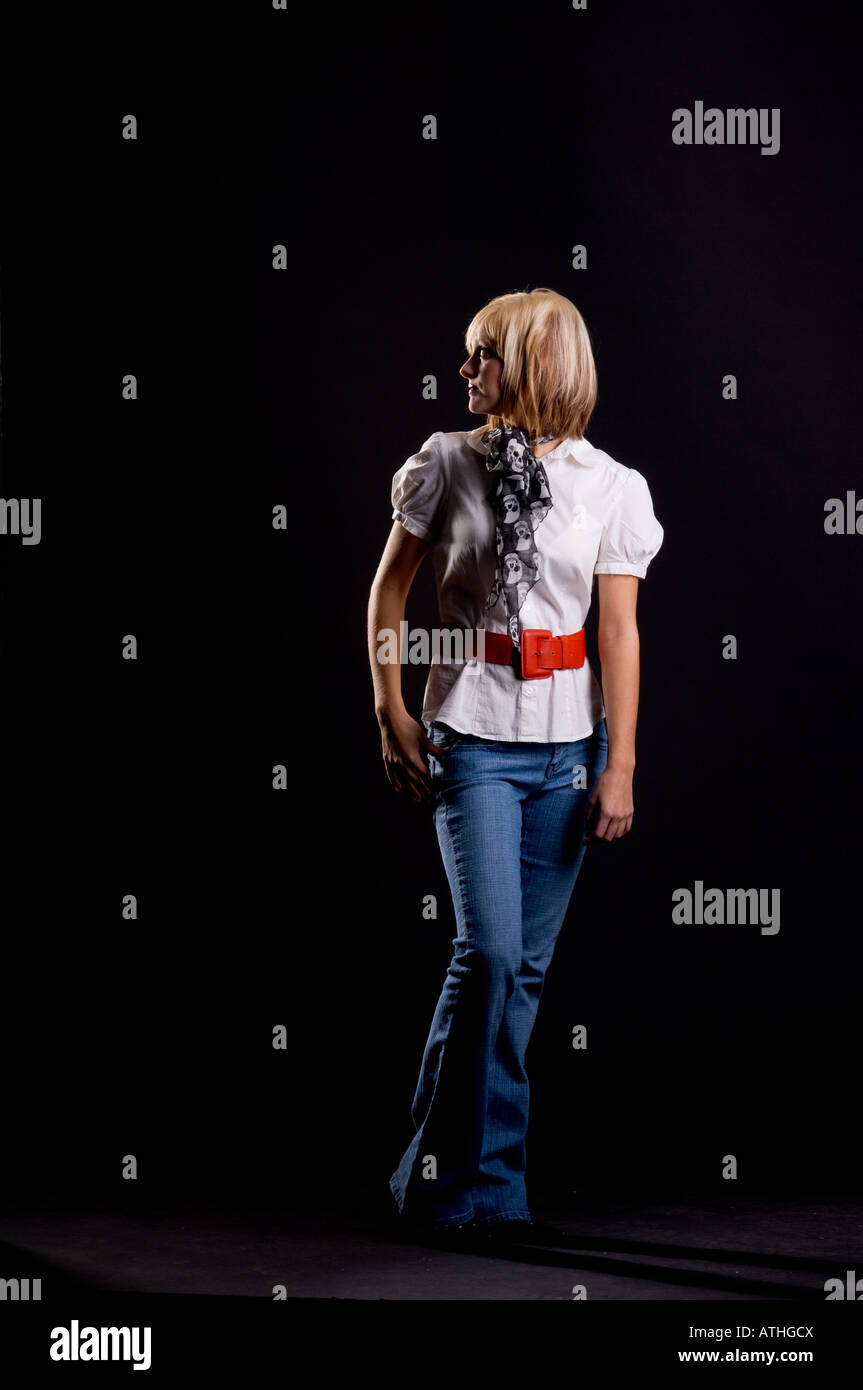Studio portrait of a blonde teenage girl wearing blue jeans and a white ...