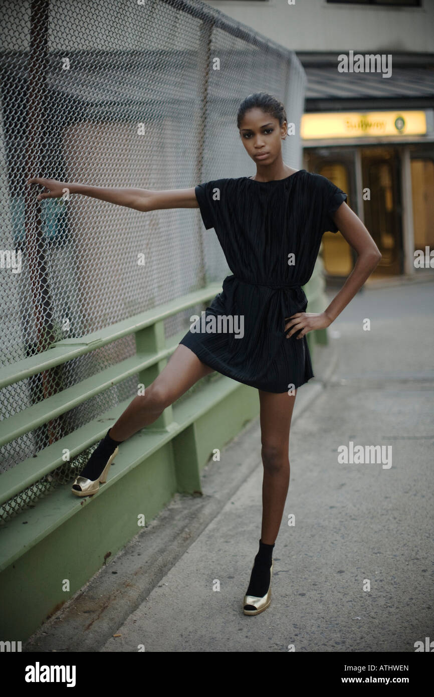 Young woman tugs on a fence while on a overpass that leads to a subway station in the Bronx Stock Photo