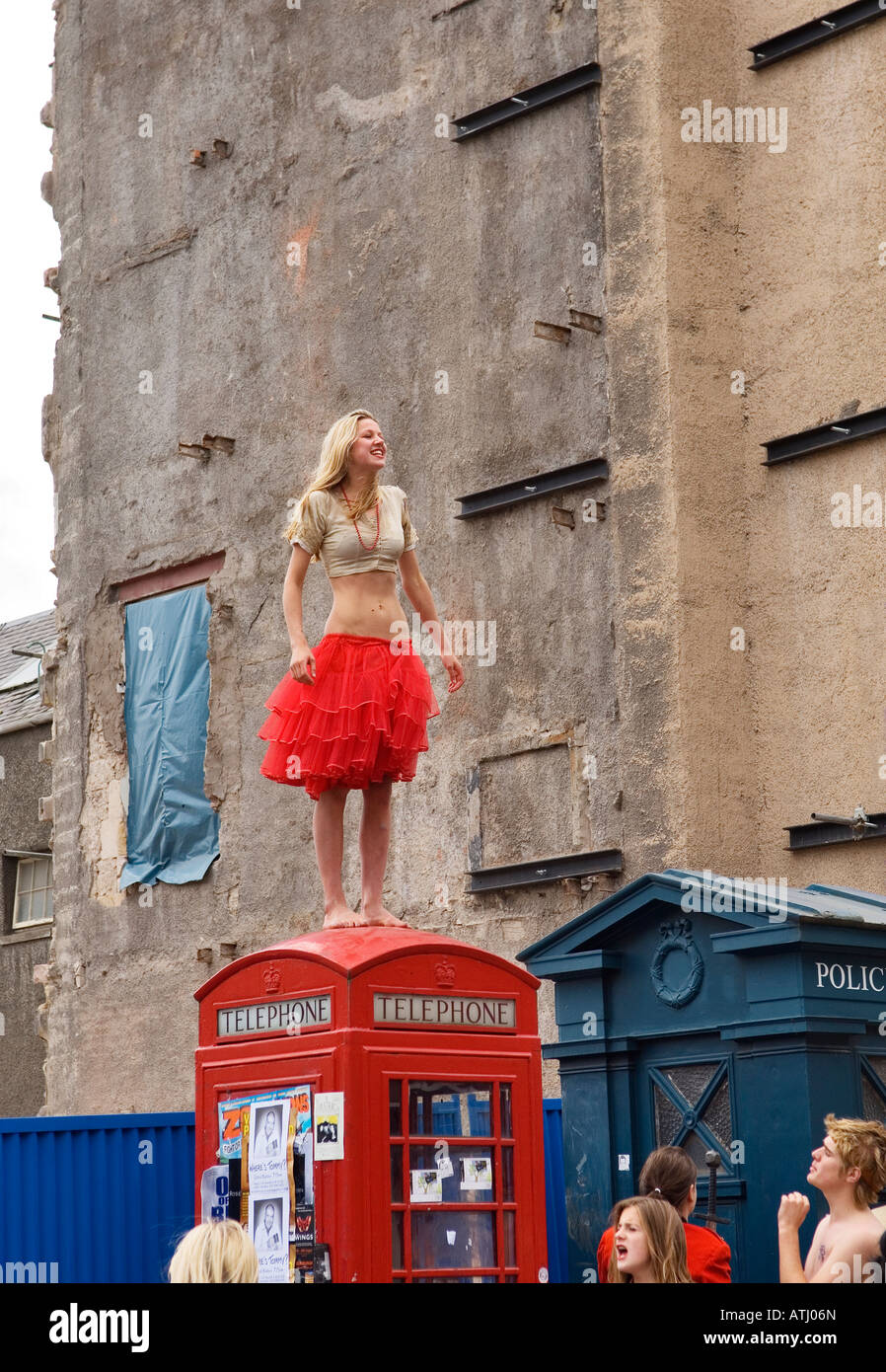 Edinburgh Festival Fringe, Scotland. Young woman promoting Fringe show stands on red telephone box in the High Street Stock Photo