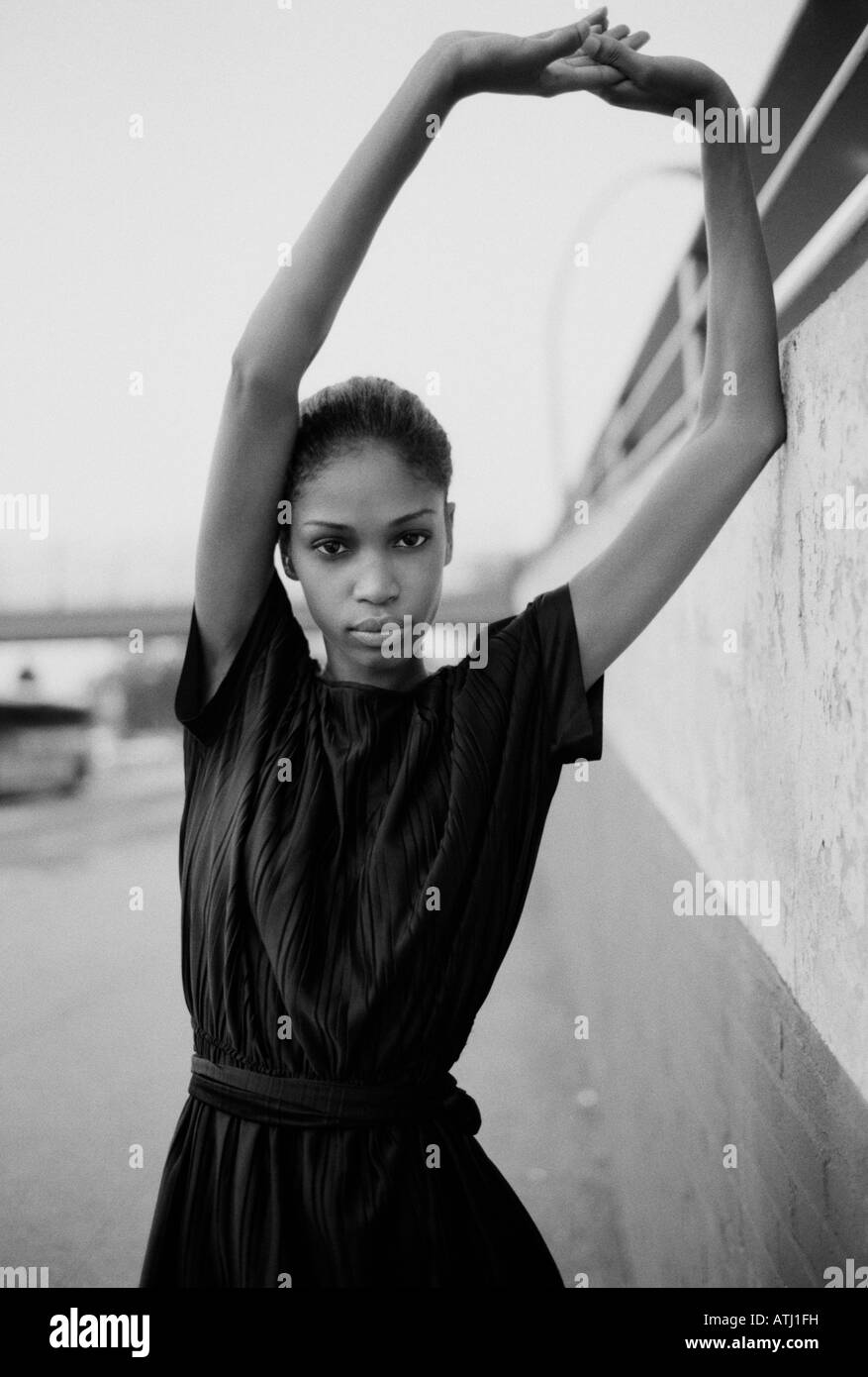 A woman wearing a little black dress leans against a wall in the Bronx Stock Photo