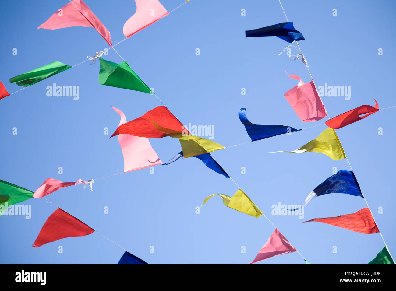 Colourful buntings or flags stretched across a blue sky background Stock Photo