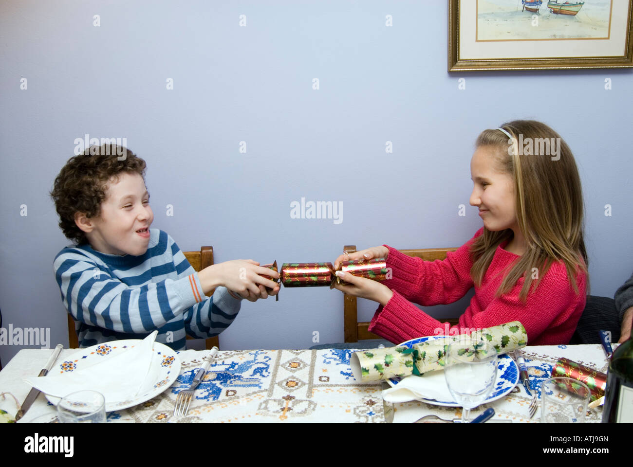 Siblings pulling Christmas cracker at lunch table England UK Stock Photo
