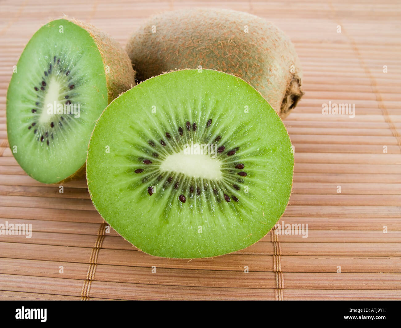 Two kiwis over a bamboo mat Stock Photo