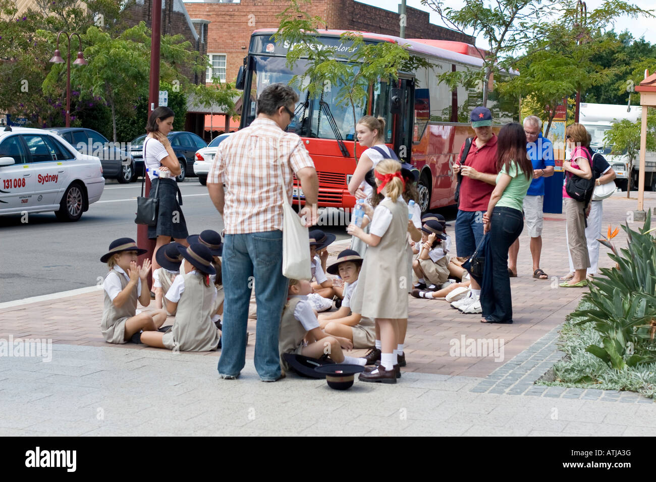 A group of school children and their teacher waiting for the bus Stock Photo