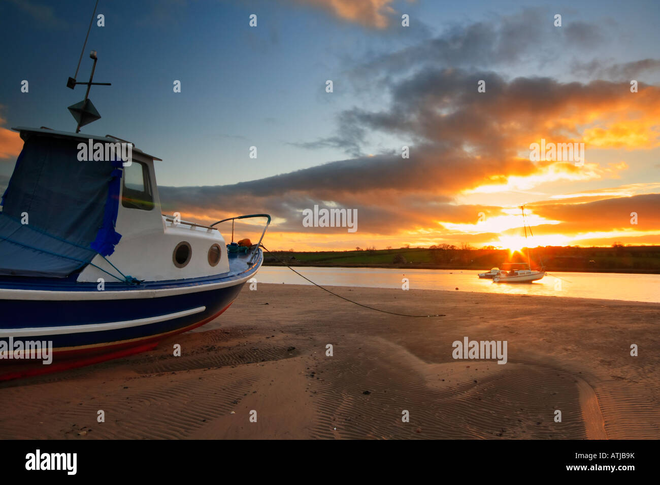 Old fishing boat moored in Alnmouth estruary at low tide and backed by ...