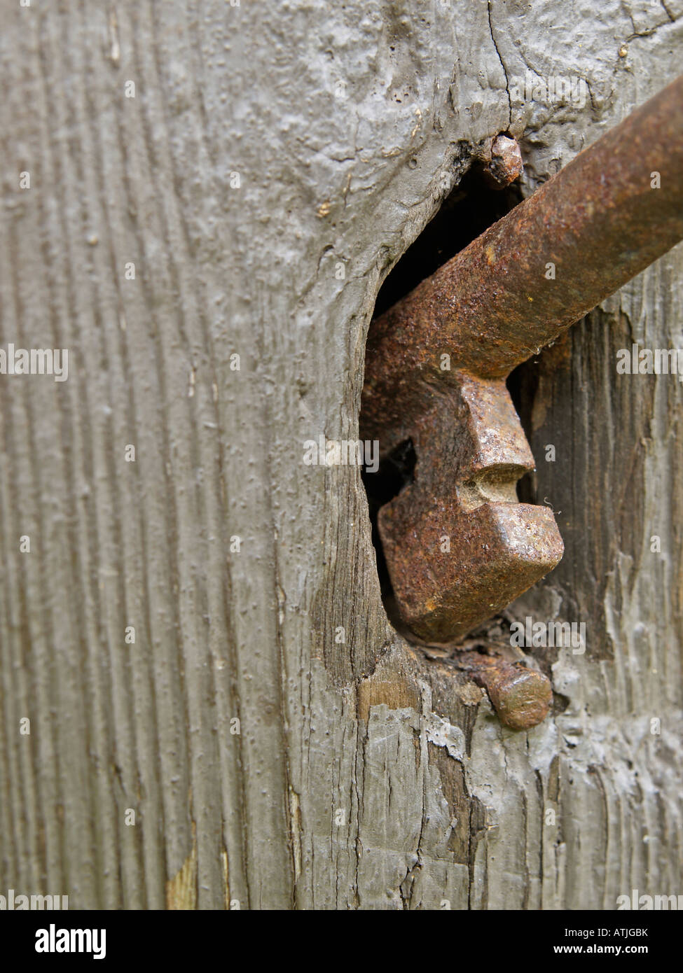sticking rusty old key in keyhole of closed old wooden door cut out