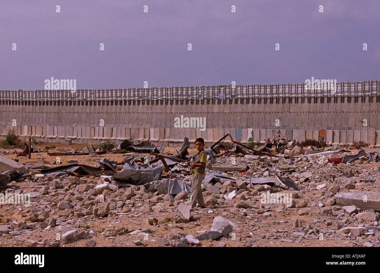 Boy playing in rubble beside security wall, Gaza Strip parallel to border with Israel Stock Photo
