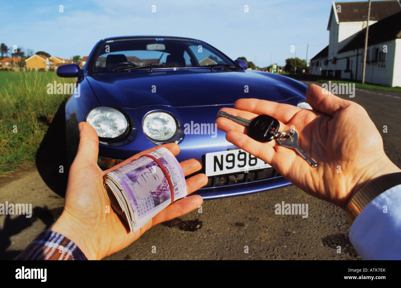 person holding wad of banknotes buying car from salesman holding car keys Leeds Yorkshire UK Stock Photo