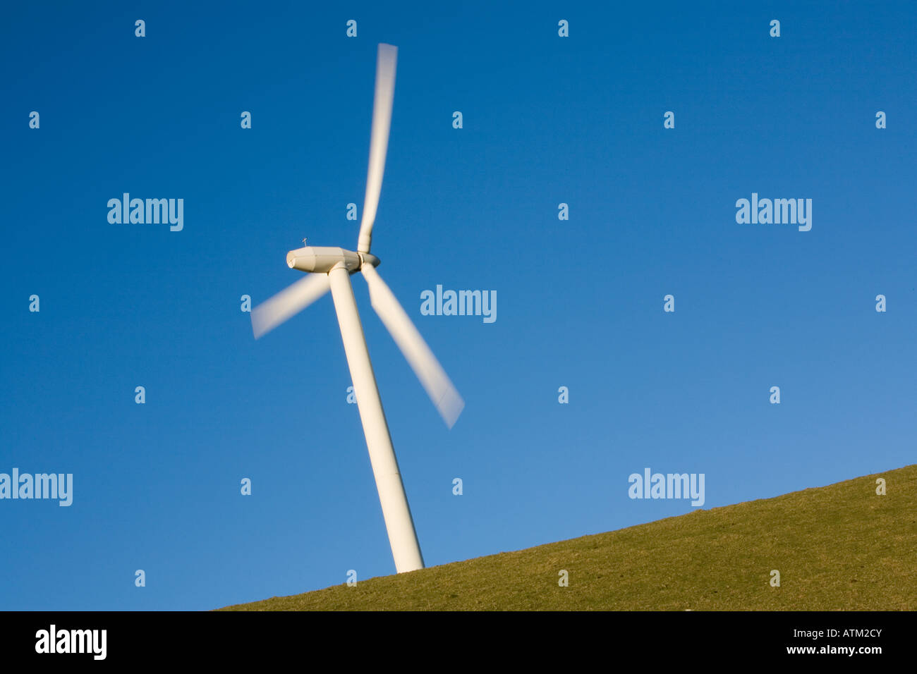 Single wind turbine showing movement against a clear blue sky on a ...