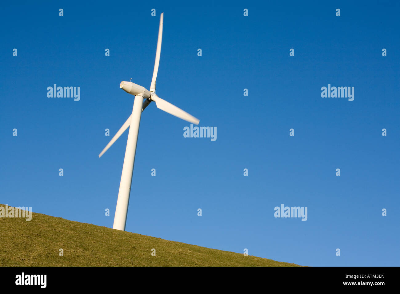 Single wind turbine against a clear blue sky on a hillside Stock Photo ...