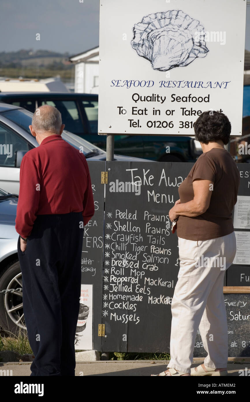 VISITORS TO WEST MERSEA NEAR COLCHESTER ESSEX LOOK AT A SEAFOOD RESTAURANT MENU Stock Photo