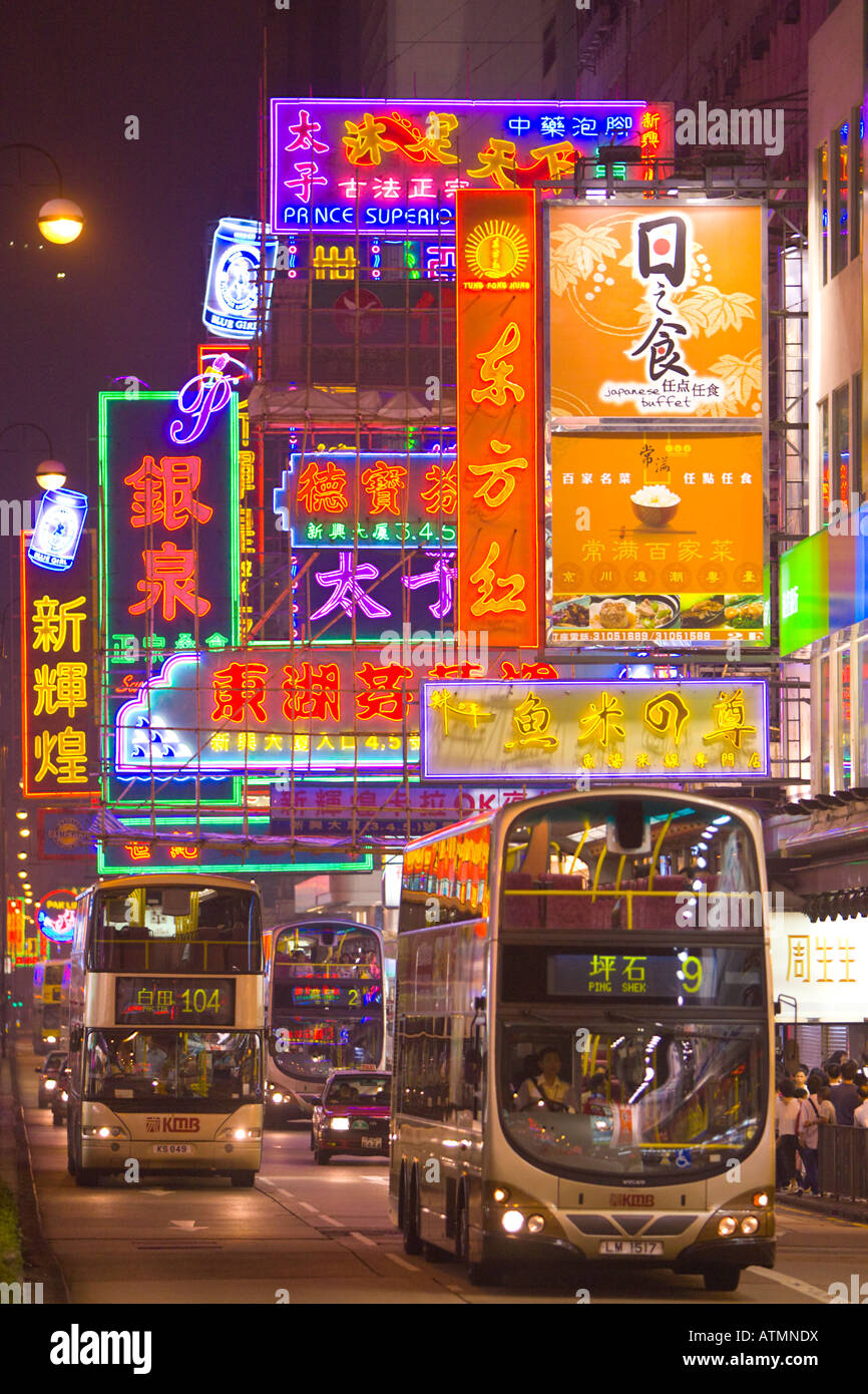 HONG KONG CHINA Colorful neon signs and bus traffic in busy neighborhood at night in Kowloon Stock Photo