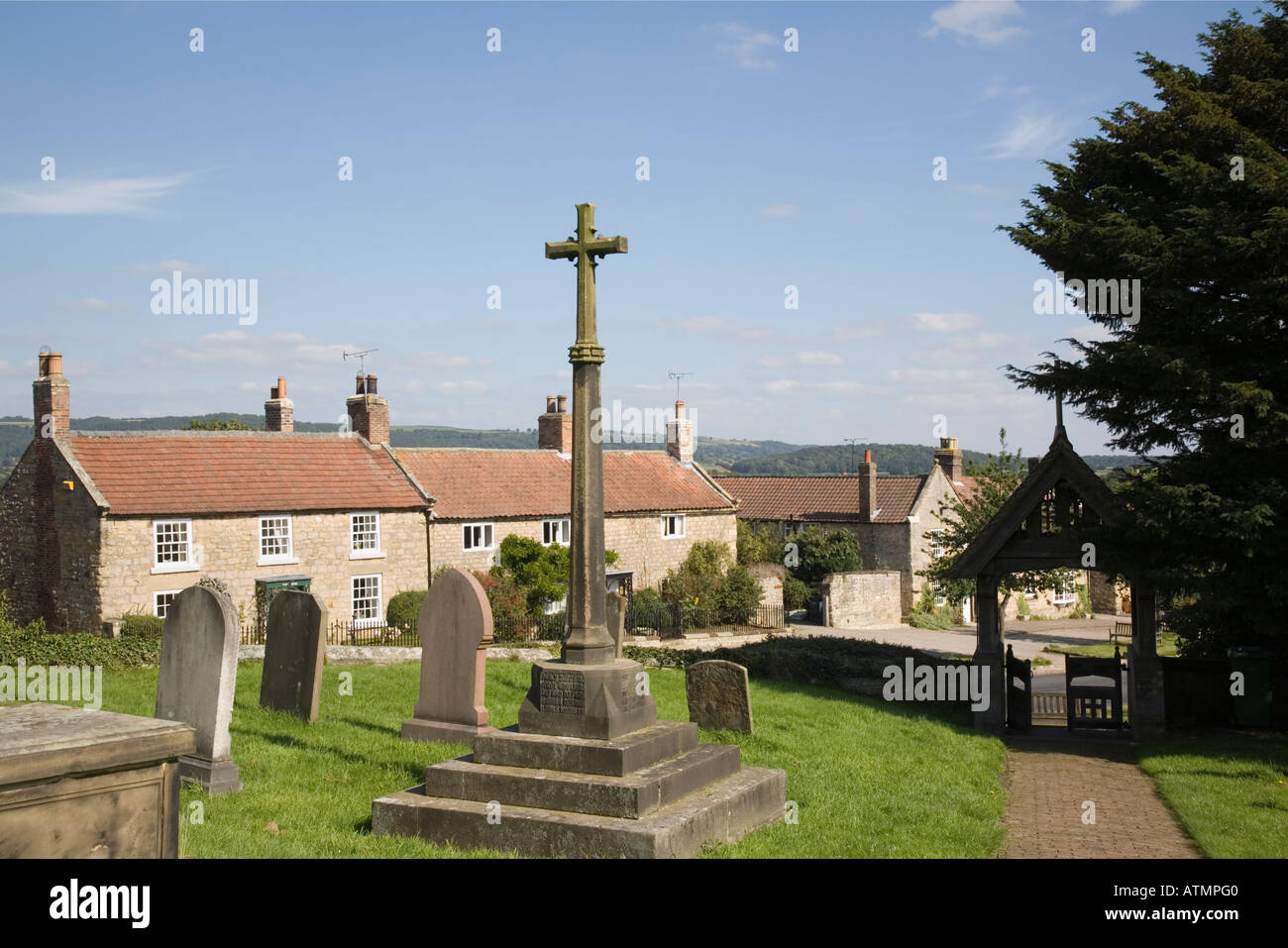 Coxwold North Yorkshire England UK. War memorial cross in church yard in peaceful picturesque village Stock Photo