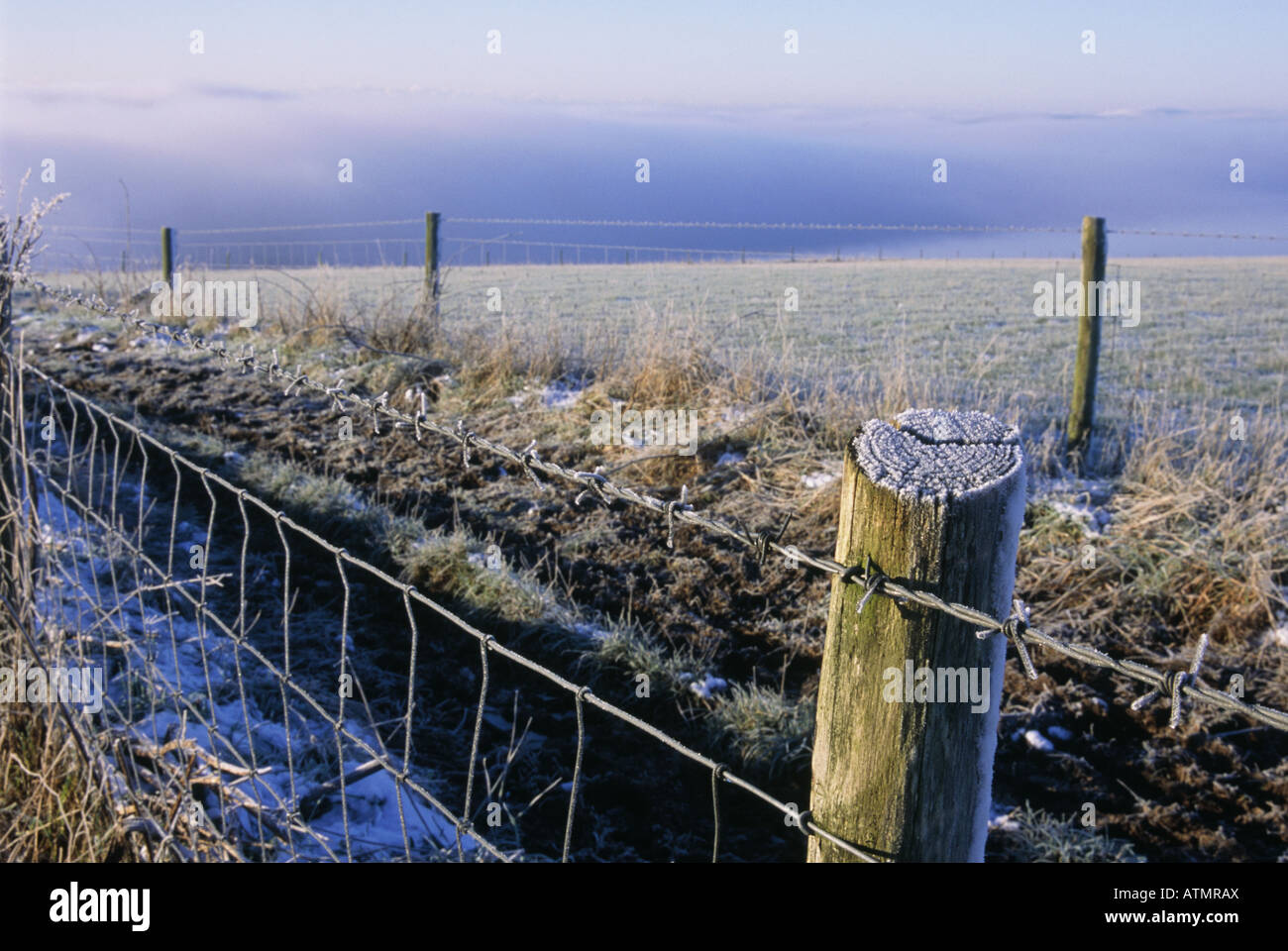 Undulating downland Frost cold weather Path post and wire Mist rising from ground Stock Photo