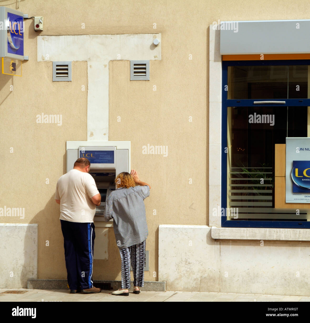 Couple Using a French Bank Cash Machine Stock Photo