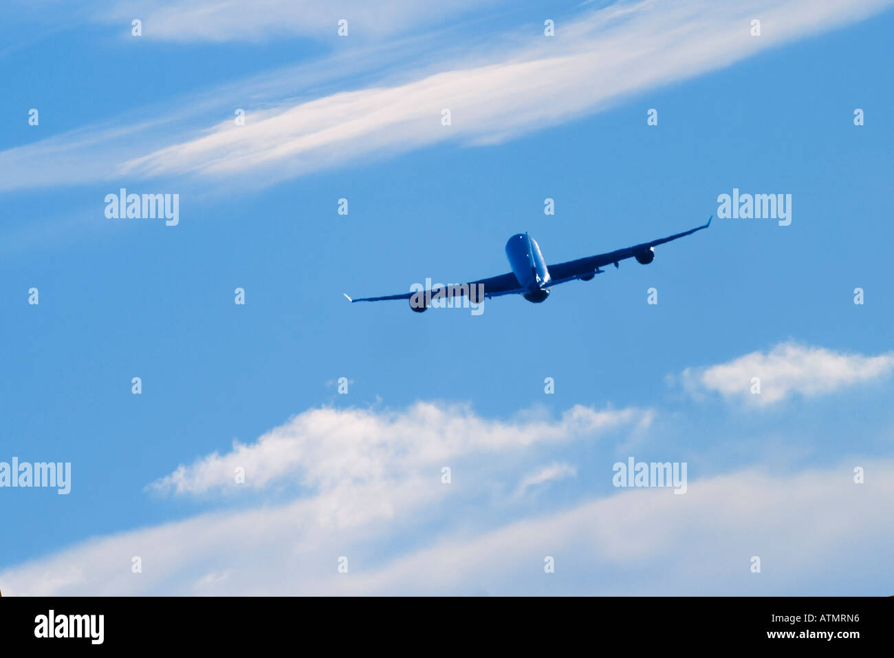 Commercial airplane flying above white clouds and blue sky Stock Photo