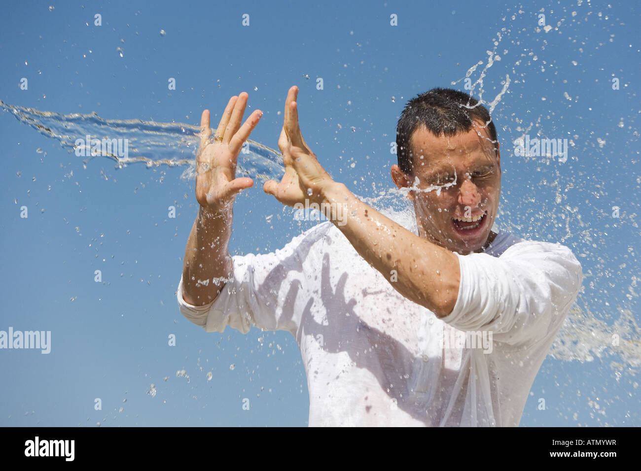 Man getting splashed with water against a blue sky Stock Photo Alamy
