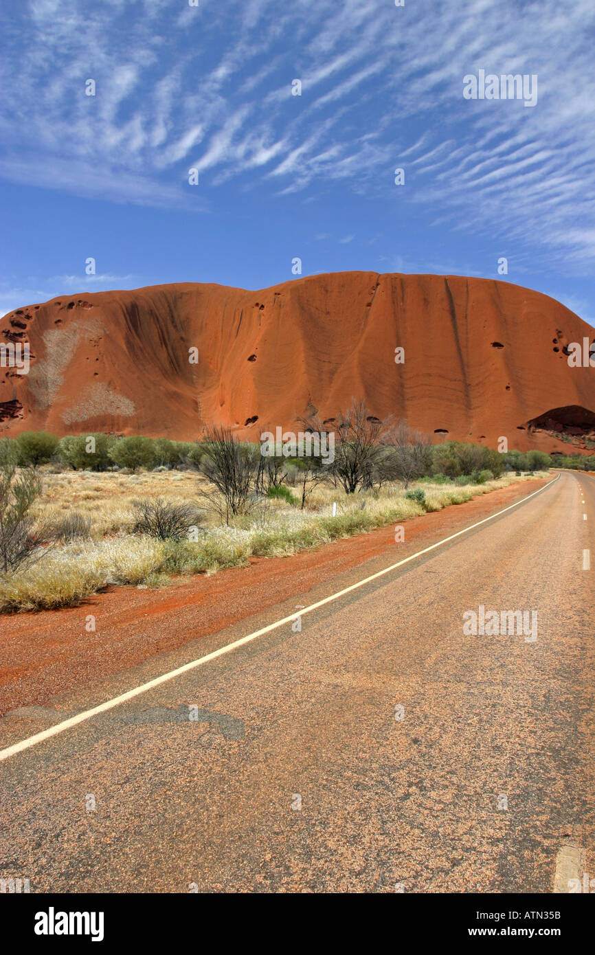 Famous tourist attraction Ayers rock Uluru and the circular ring road deserted in late afternoon sun Australia Stock Photo
