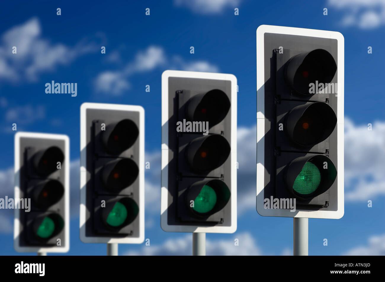 ROW OF FOUR ROAD TRAFFIC LIGHTS SHOWING GREEN Stock Photo