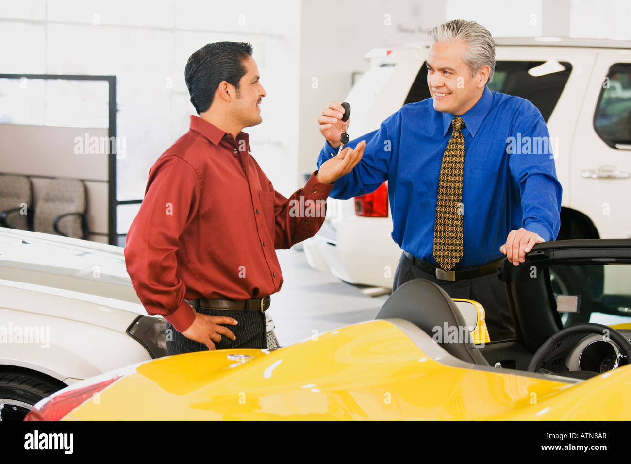 Hispanic car salesman handing car keys to buyer Stock Photo