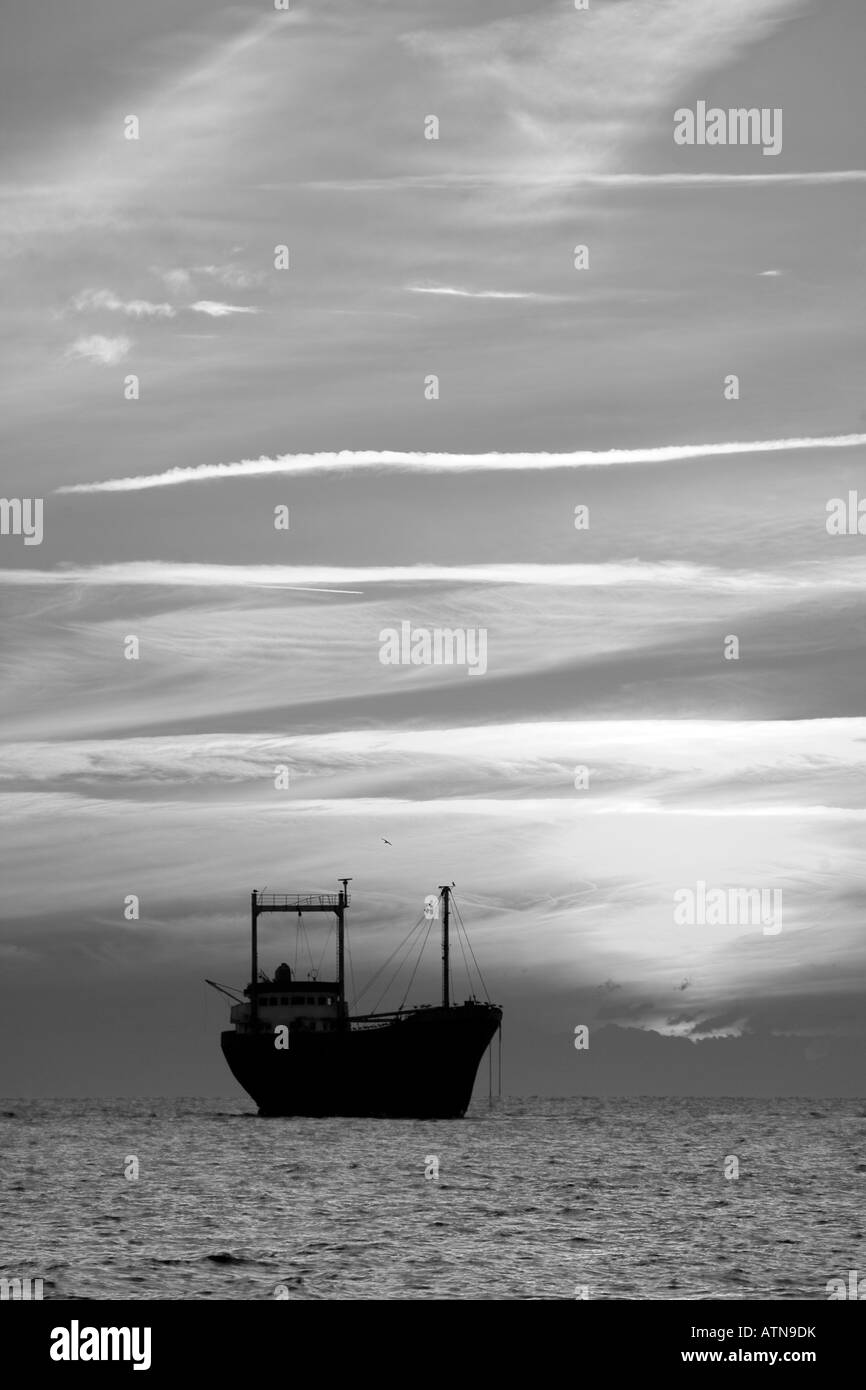 Beached, grounded silhouetted shipwrecked vessel; Cargo ship Honduran-flagged M/V Demetrios II at sunset which ran aground in Pathos Cyprus in 1998 Stock Photo